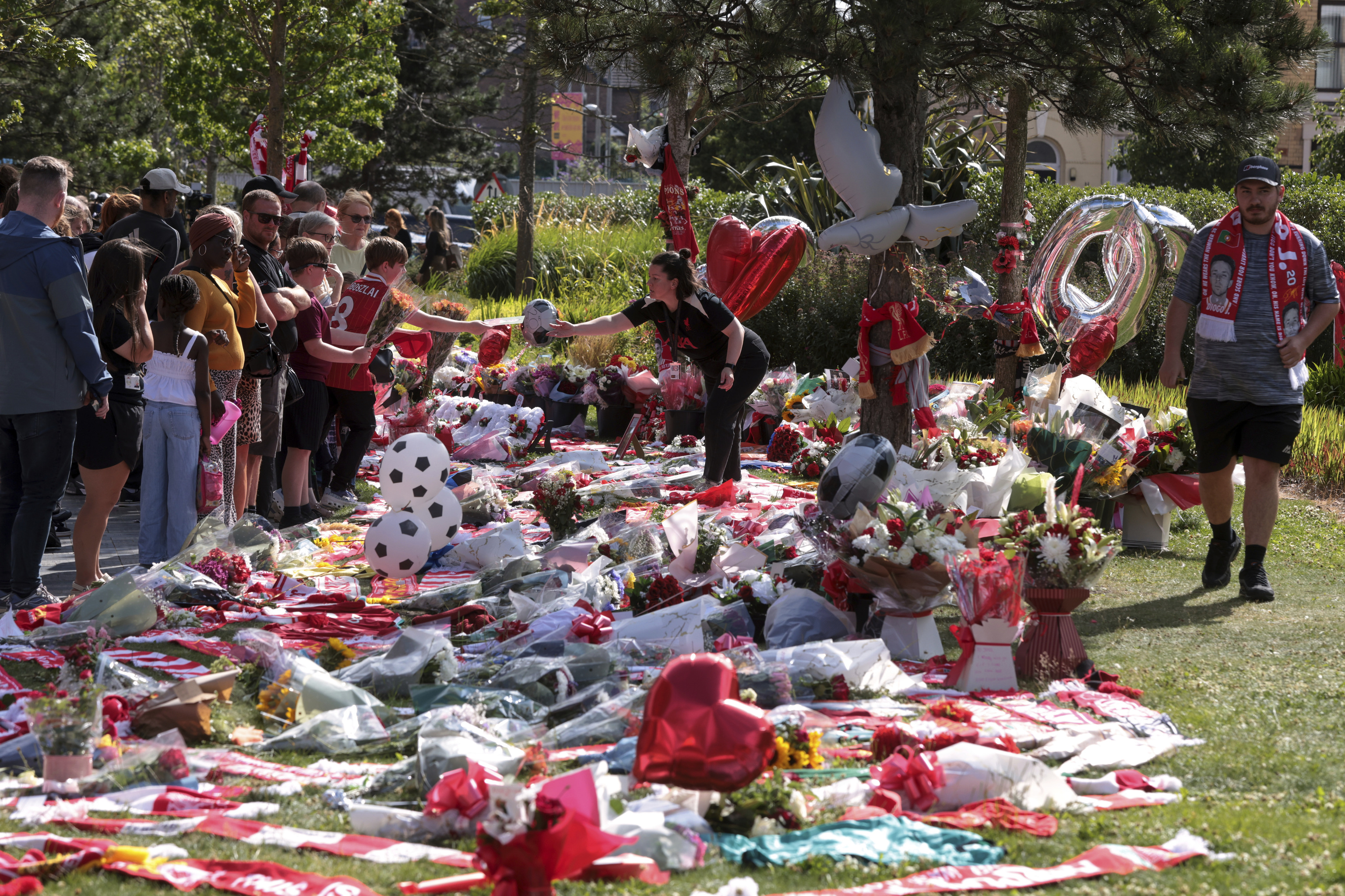 Football fans stand next to tributes in memory of Liverpool player Diogo Jota at Anfield.