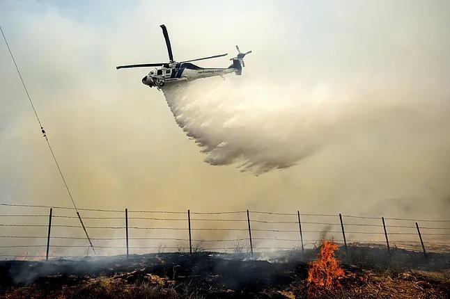 A helicopter is assisting in the firefighting efforts.