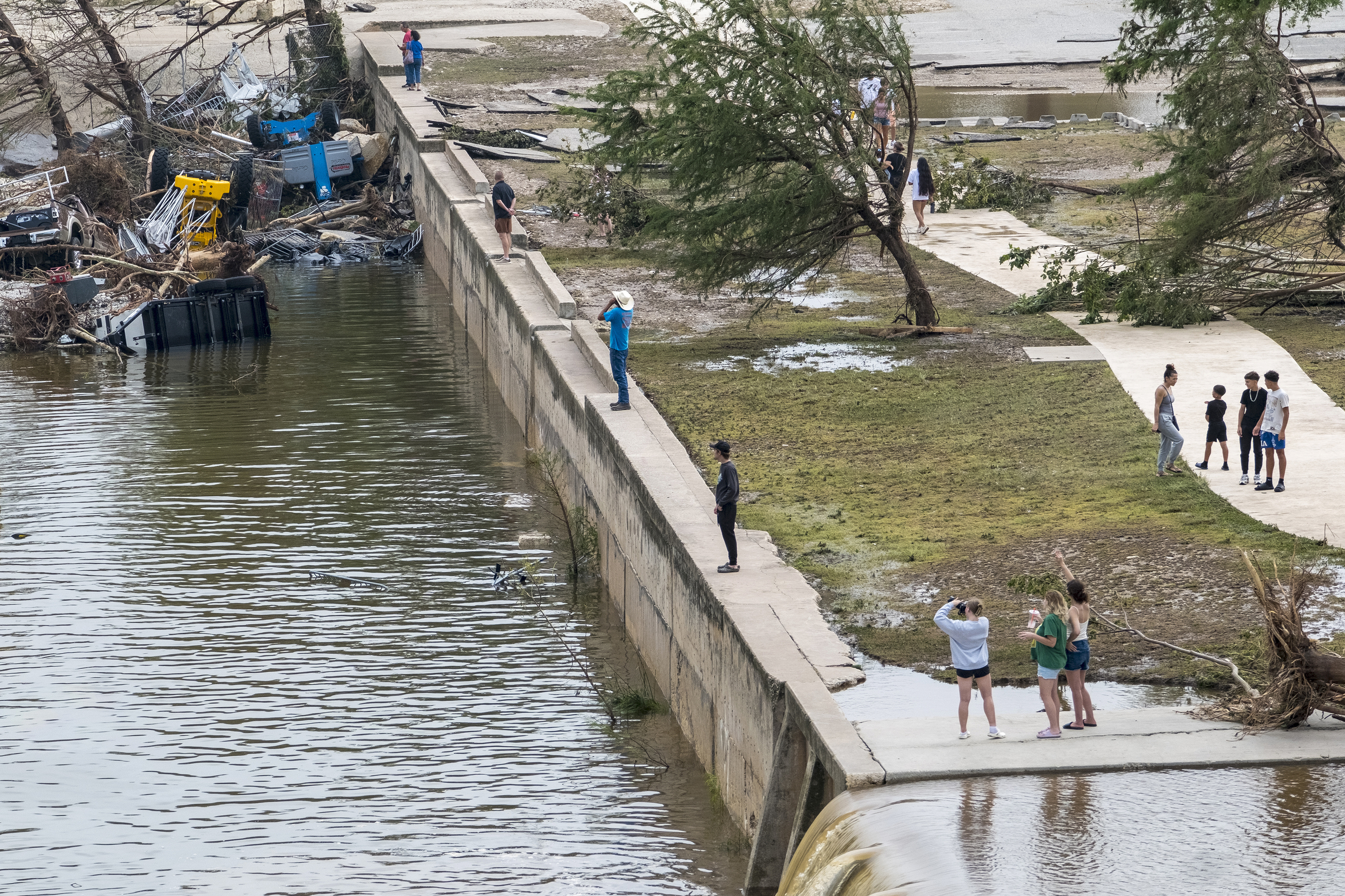 Onlookers walk along the banks of the Guadalupe River.