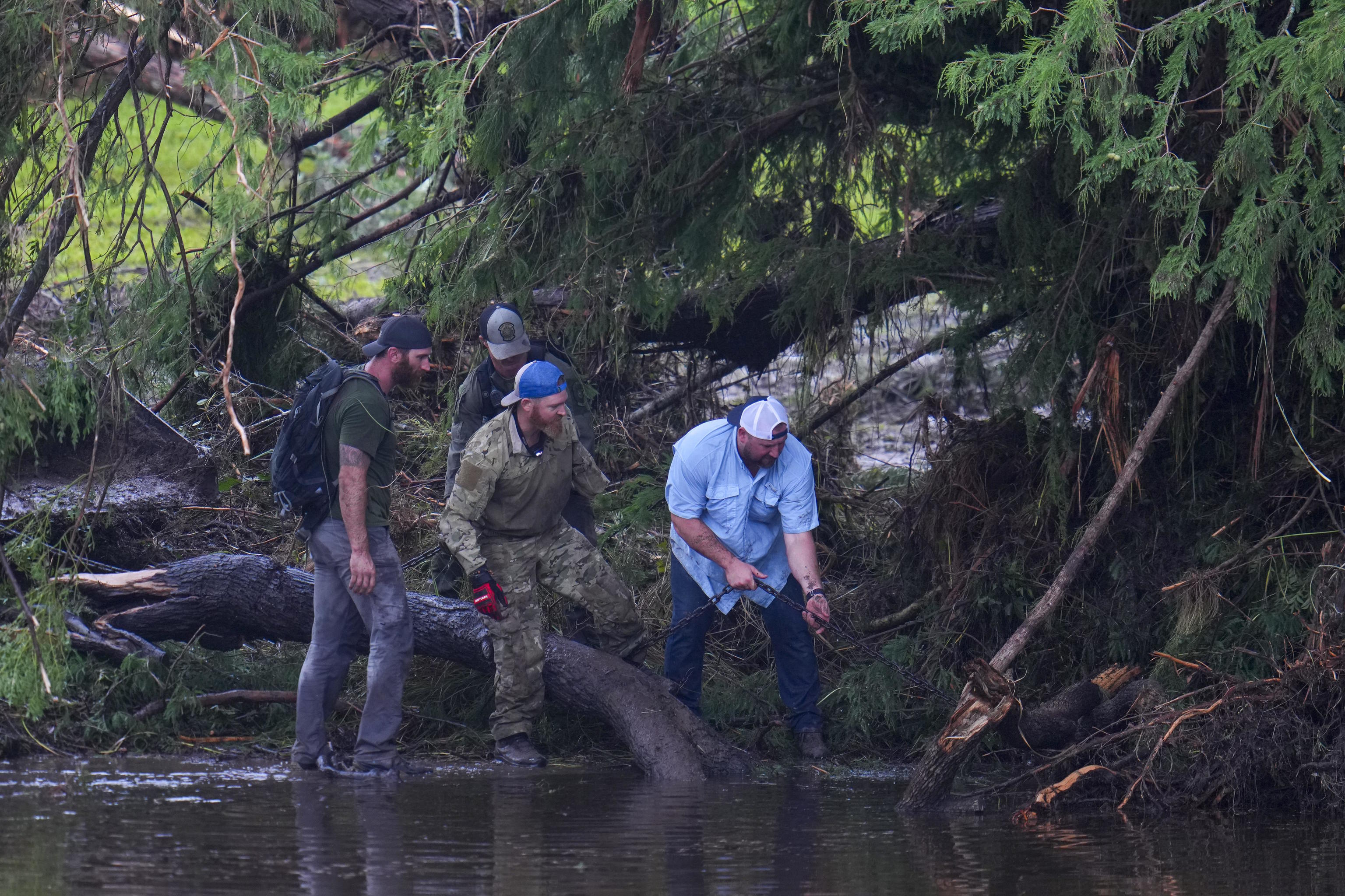 People remove debris from the Guadalupe River while inspecting an area.