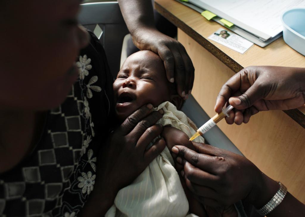 A mother holds her baby receiving a new malaria vaccine