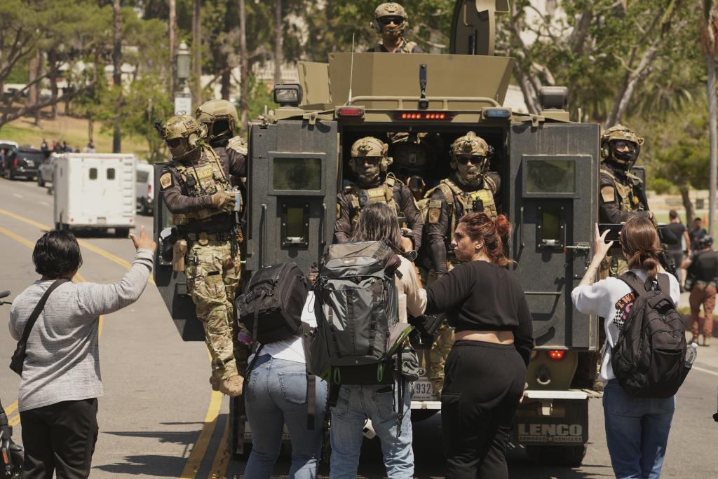 Federal agents ride on and armored vehicle at MacArthur Park