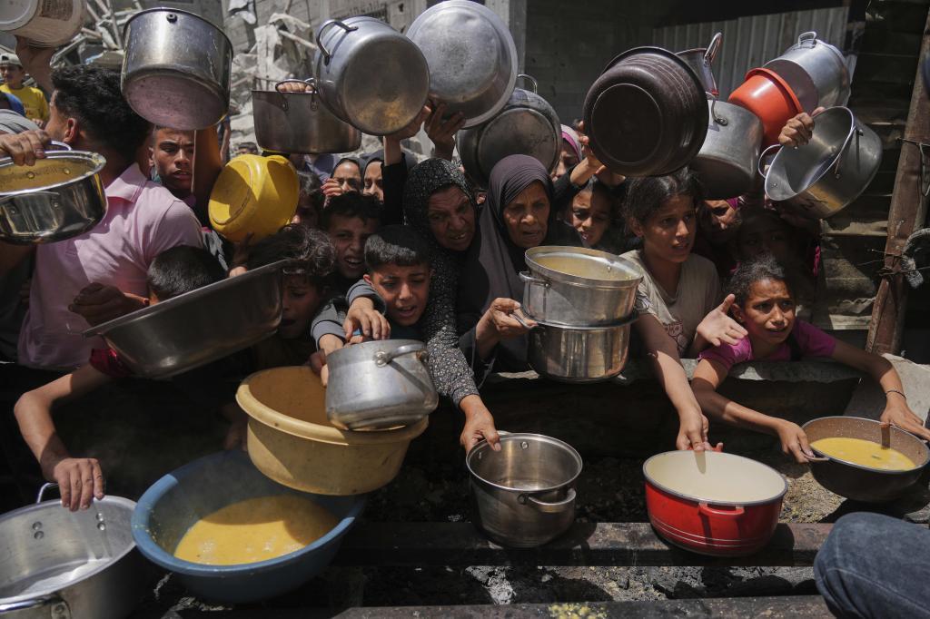 Palestinians struggle to get donated food at a community kitchen.