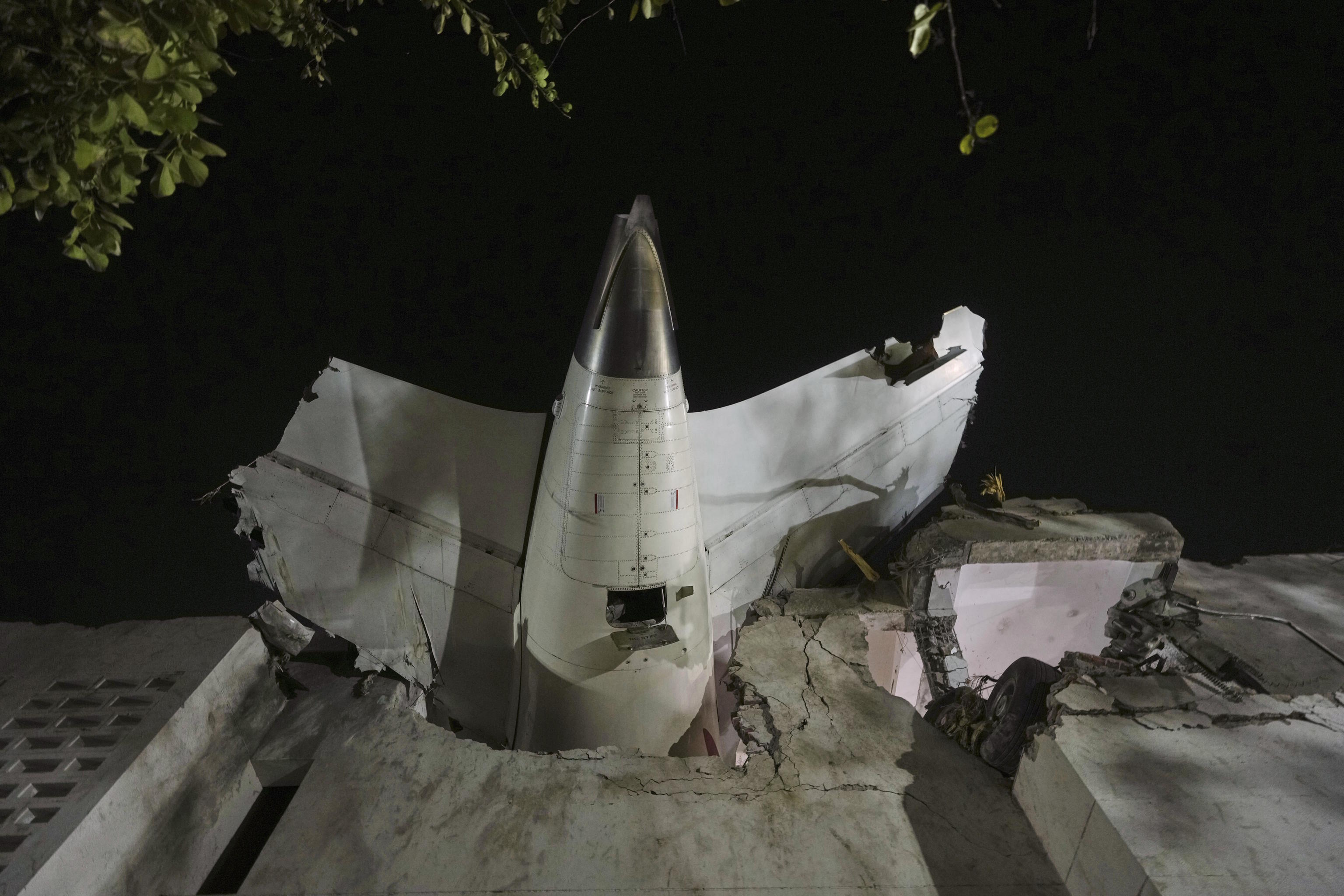 The tail of the airplane crashed is seen stuck in a building in India.