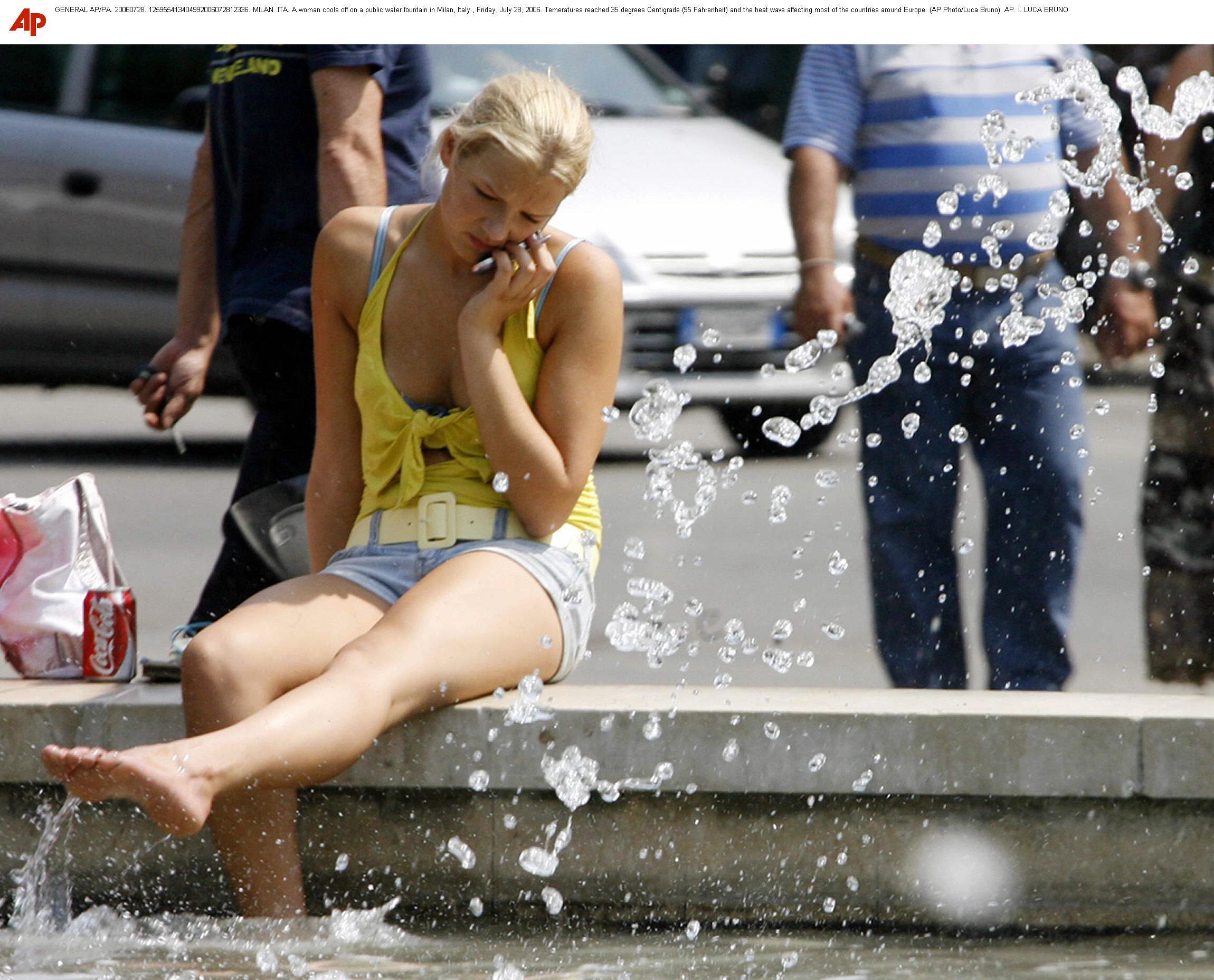 A woman cools off on a public water fountain in Milan, Italy.
