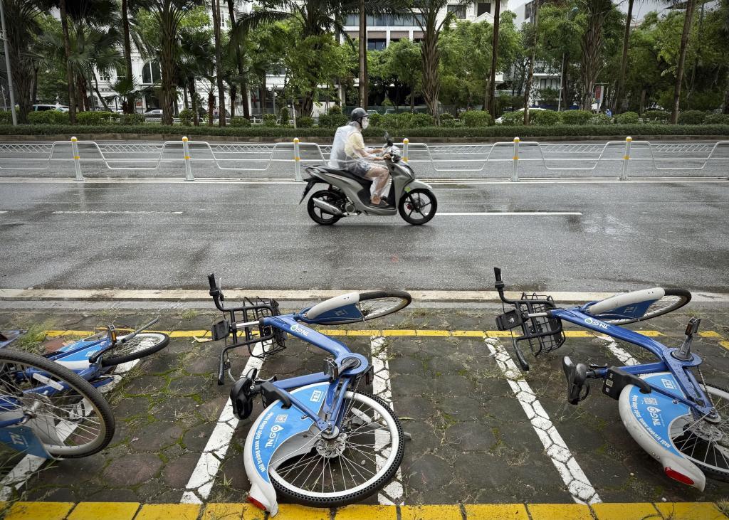 A motorcyclist drives past fallen bicycles in the rain.