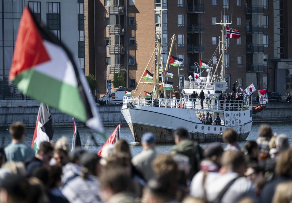 Demonstrators carrying Palestinian flags look on as the Ship to Gaza.
