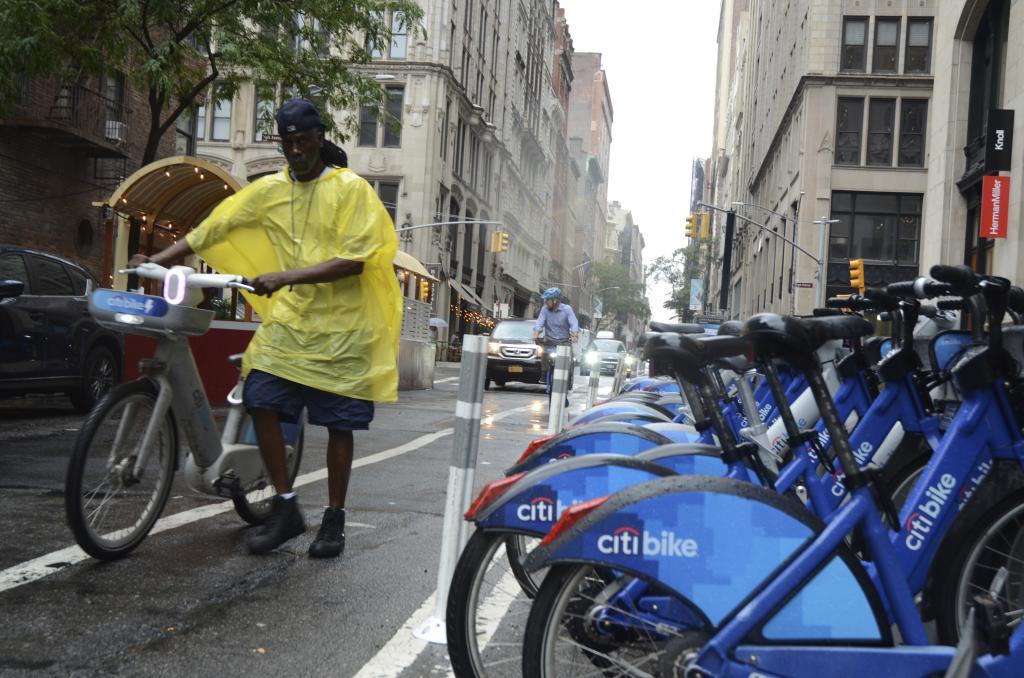 People ride bikes in the rain on Second Avenue and 20th Street in NY.