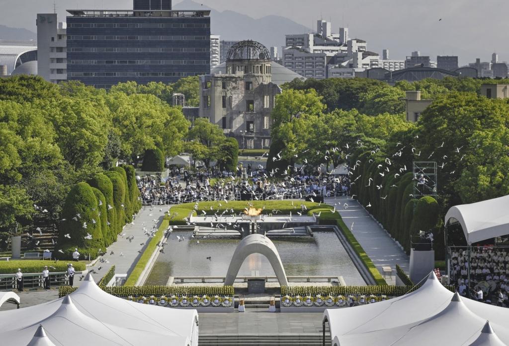 Pigeons fly over the cenotaph dedicated to the victims of the atomic bomb in Hiroshima Peace Park.