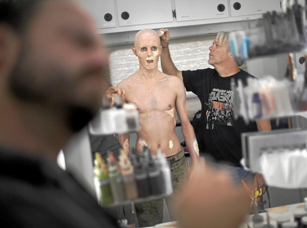 Makeup session for his zombie characterization by makeup artists (left and right) for the filming of the television series "The Walking Dead."