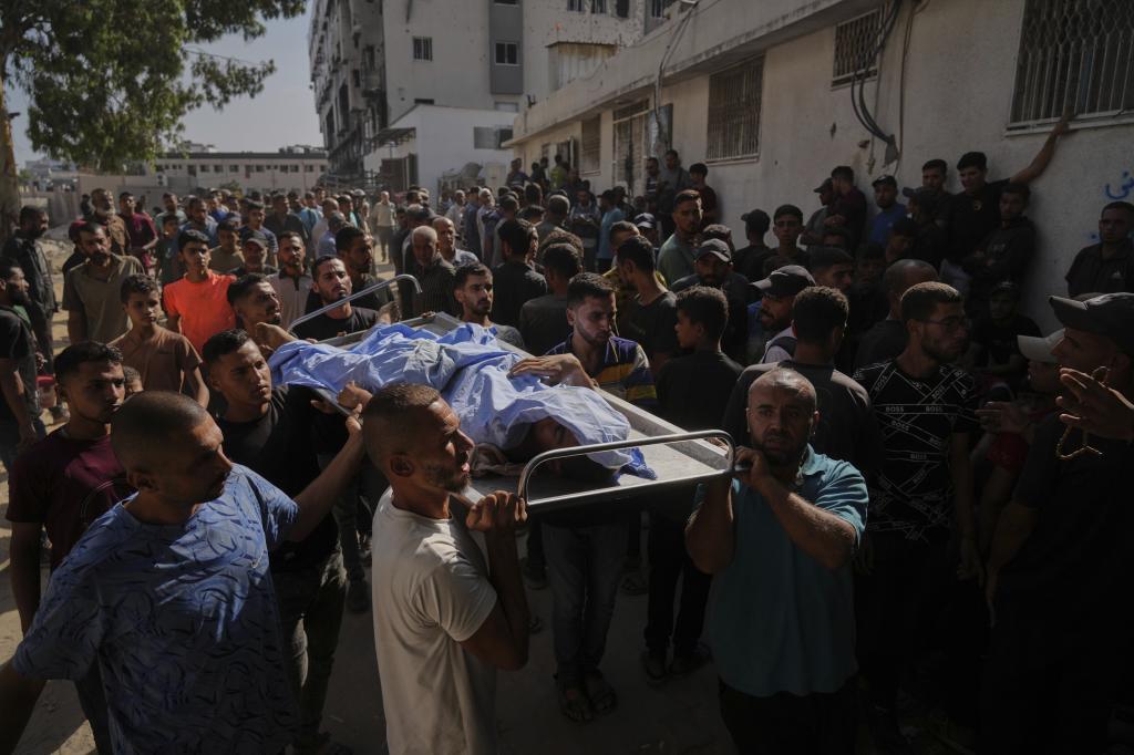 Palestinians carry the body of a person who was killed while trying to reach aid trucks entering northern Gaza Strip through the Zikim crossing with Israel