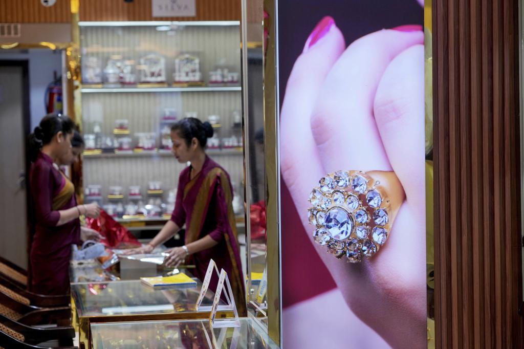 Shop attendants arrange pieces of jewelry on a display counter at a store in Lucknow