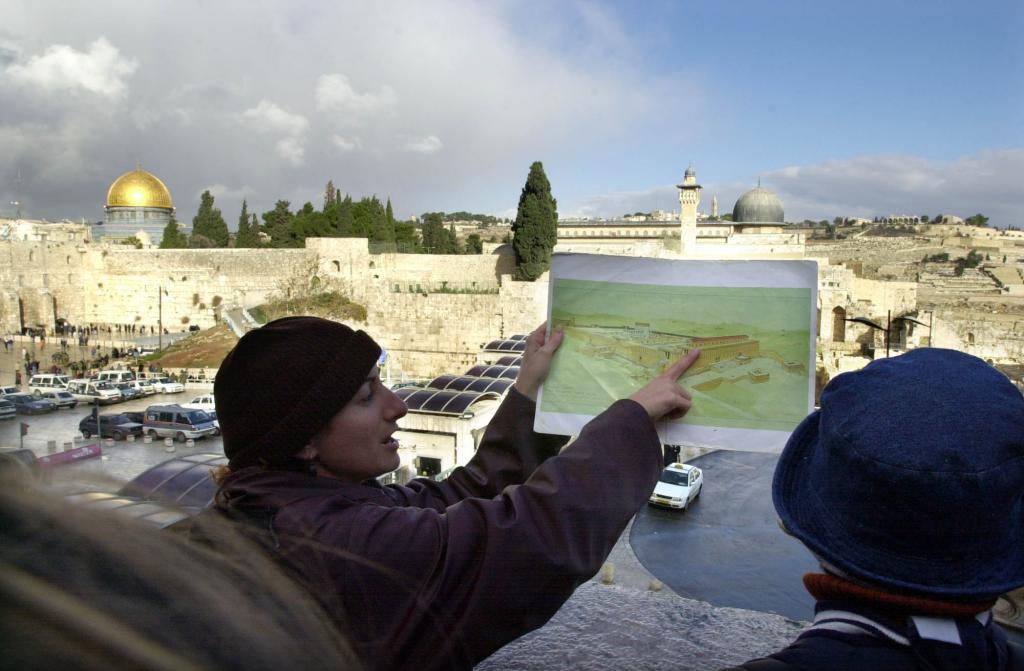 A tour guide shows a group of tourists a panoramic view of Jerusalem.