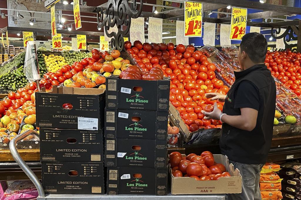 Employee works to restock tomatoes at a grocery store in Wheeling,
