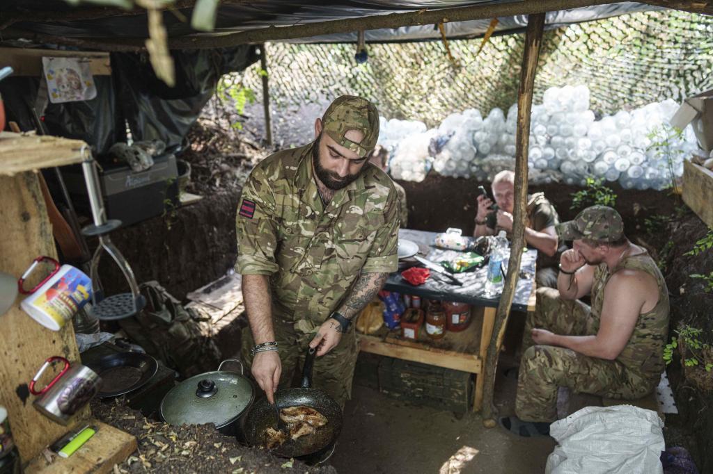 Ukrainian serviceman, aka Bronson, of the 148th artillery brigade fries meat at the frontline in Zaporizhzhia region