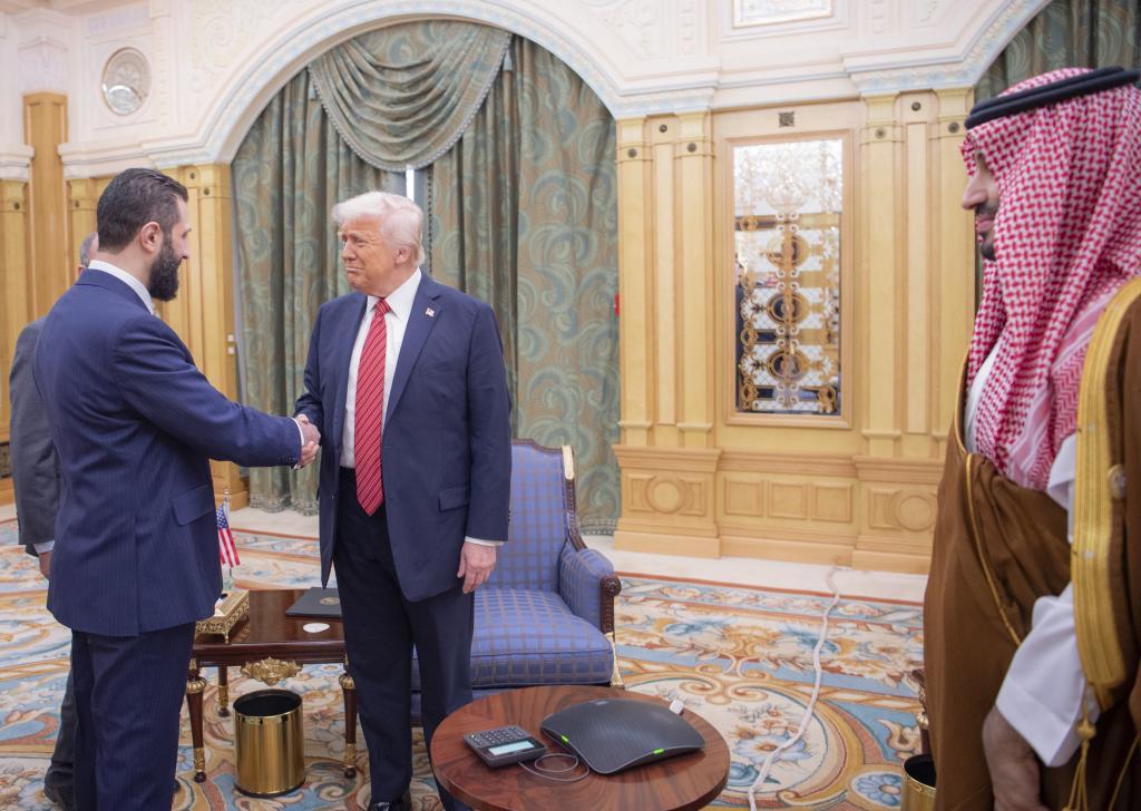Syria's interim President Ahmad al-Sharaa, left, shakes hands with President Donald Trump, centre