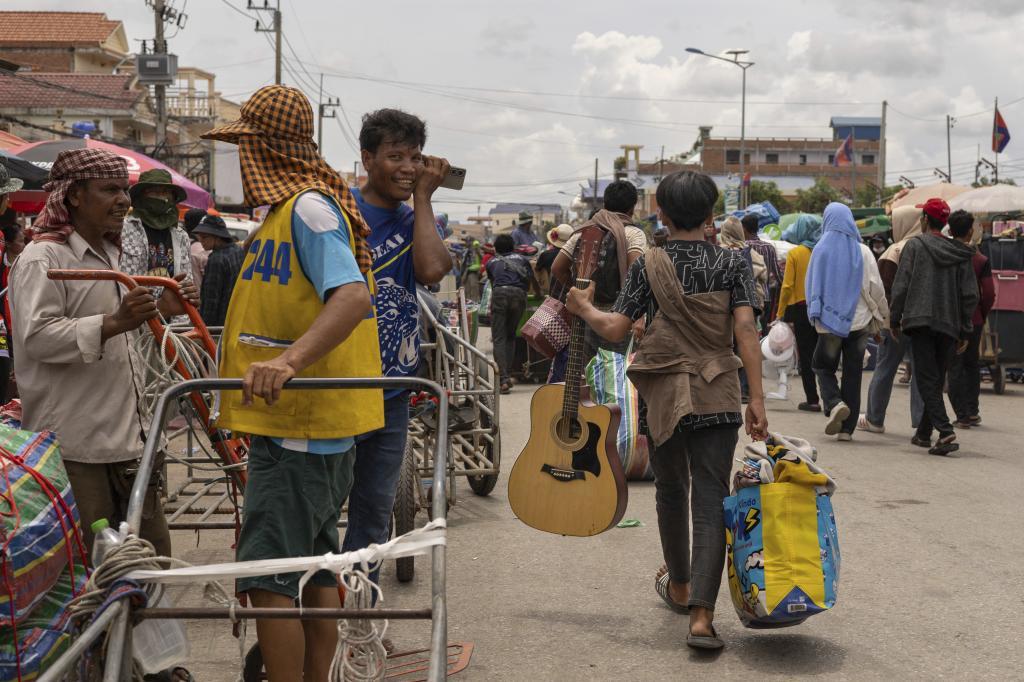 With a guitar in hand, a Cambodian migrant worker carries his belongings in Kamrieng