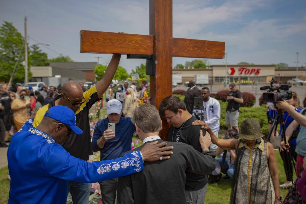 A group prays at the site of a memorial for the victims of the Buffalo supermarket shooting outside the Tops Friendly Market