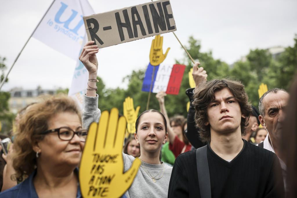 People gather, one holding an anti National Rally poster, at Republique plaza in a protest against the far-right