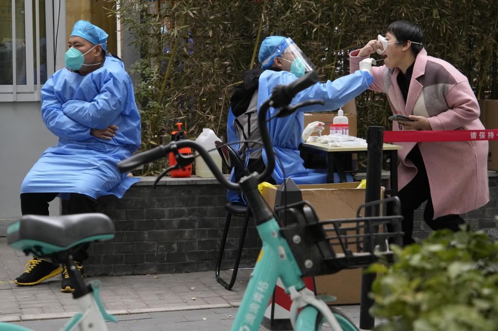 A woman lifts her mask to get swabbed for COVID test in Beijing