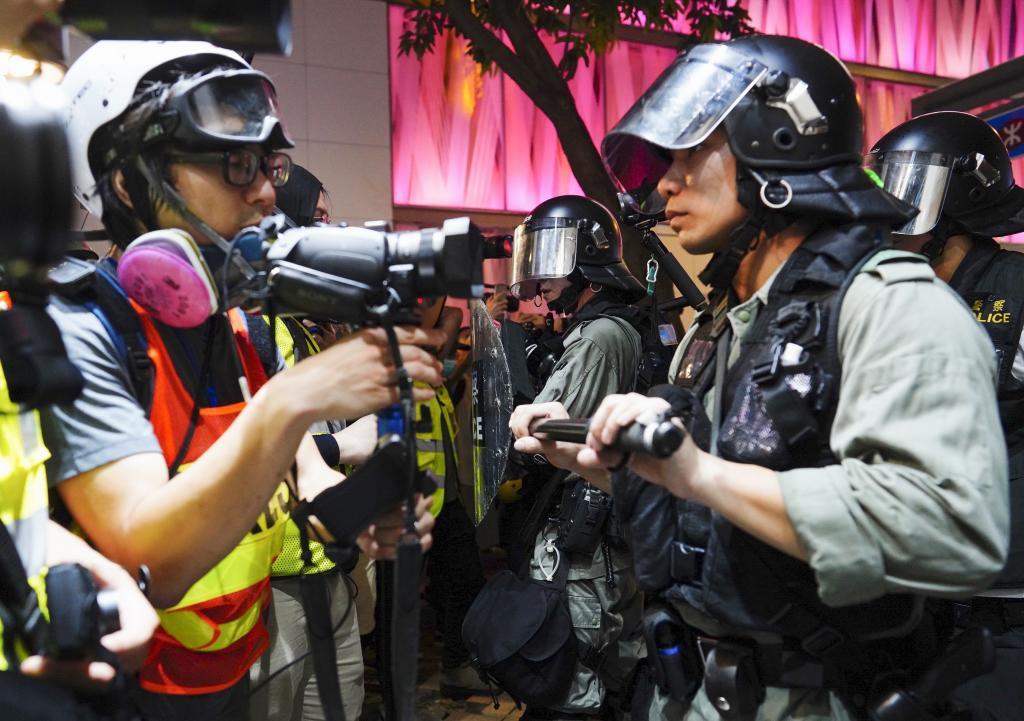 Riot police stop members of the media as they detain protesters in Hong Kong