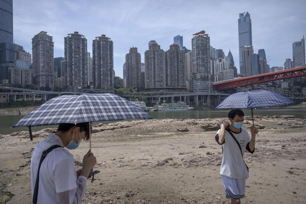 Students carrying umbrellas stand on the dry riverbed of the Jialing River in southwestern China's Chongqing Municipality