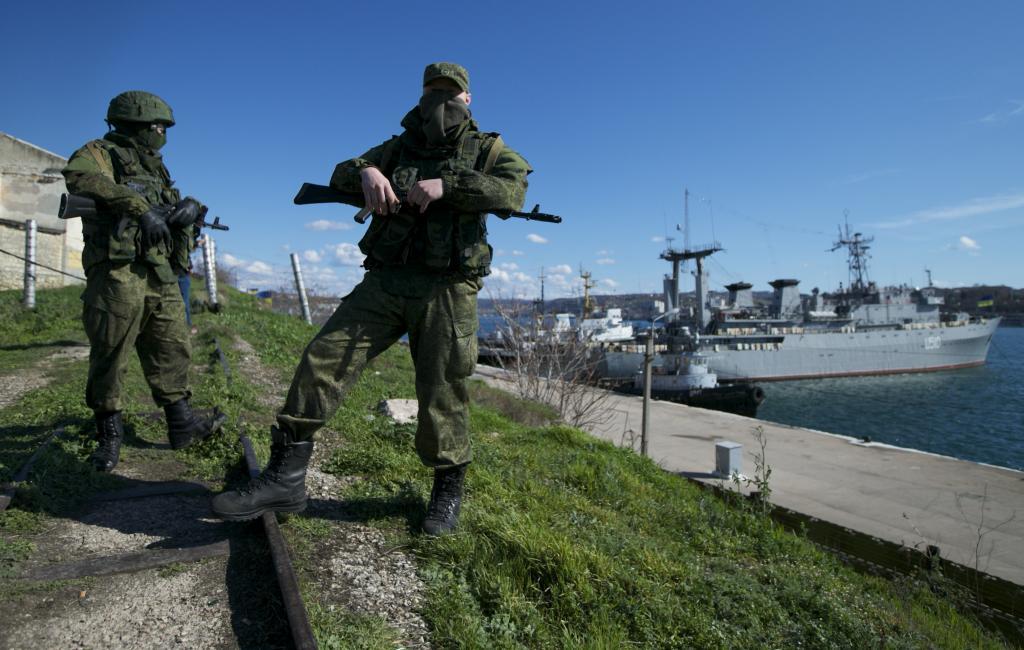 Russian soldiers guard a pier where two Ukrainian naval vessels are moored,