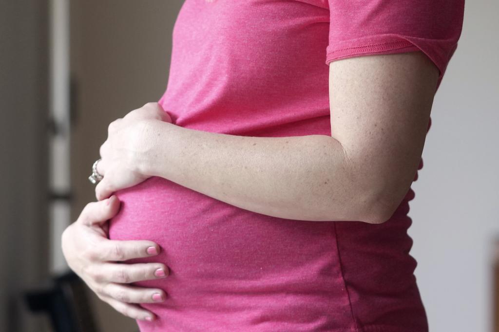 A pregnant woman stands for a portrait in Dallas