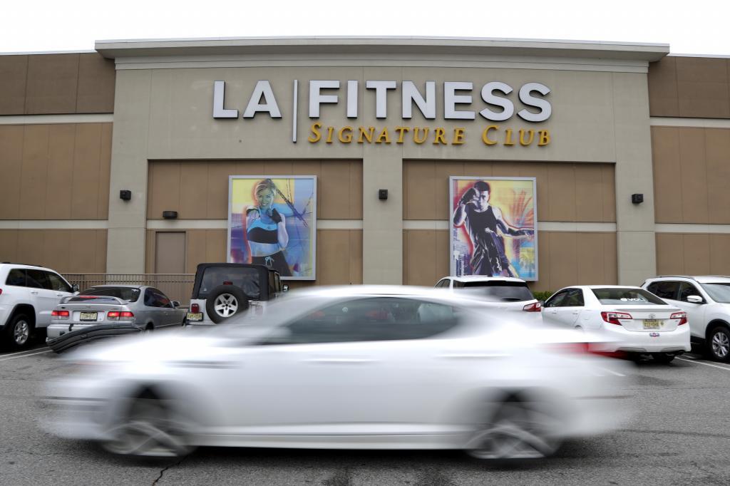 A vehicle drives near the side of the building of an LA Fitness gym