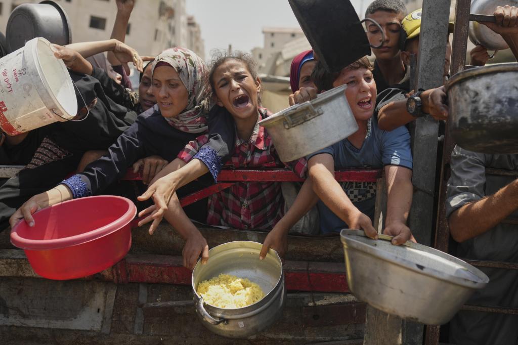 Palestinians try to get food at a soup kitchen in Gaza City.