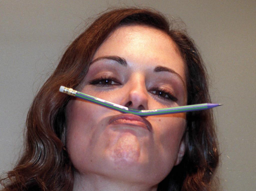 A woman shows the first flexible pencil between her nose and lip.