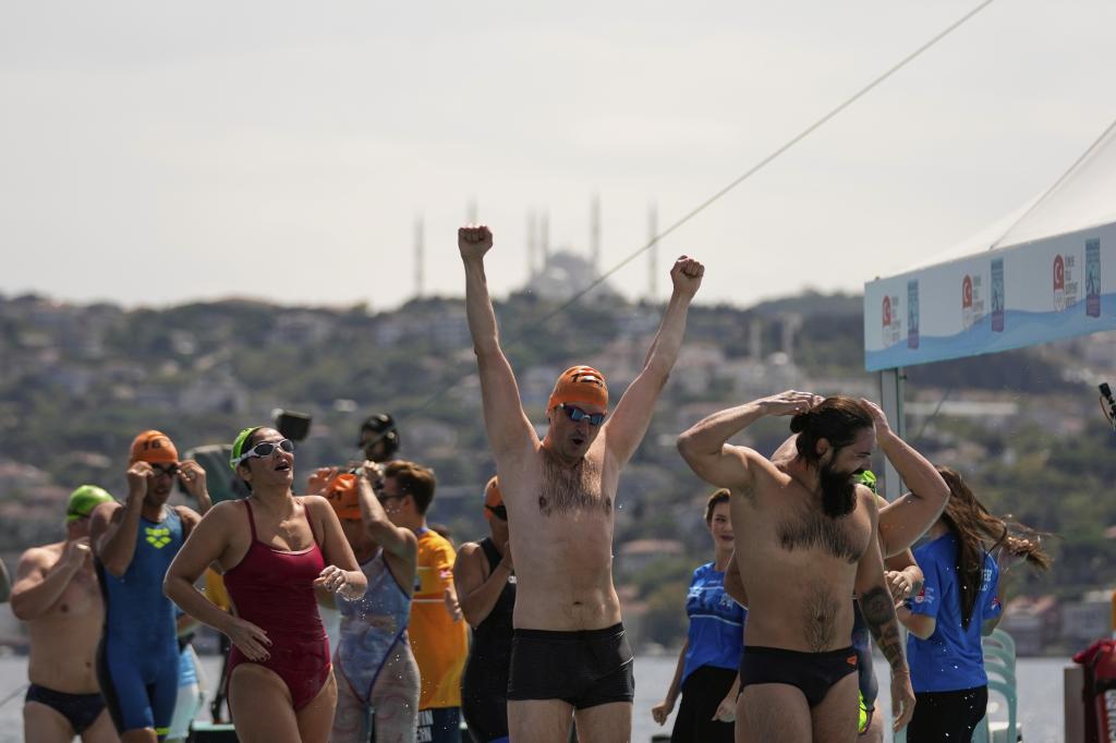Competitors celebrate after finishing a 6.5 km swimming race across the Bosphorus Strait