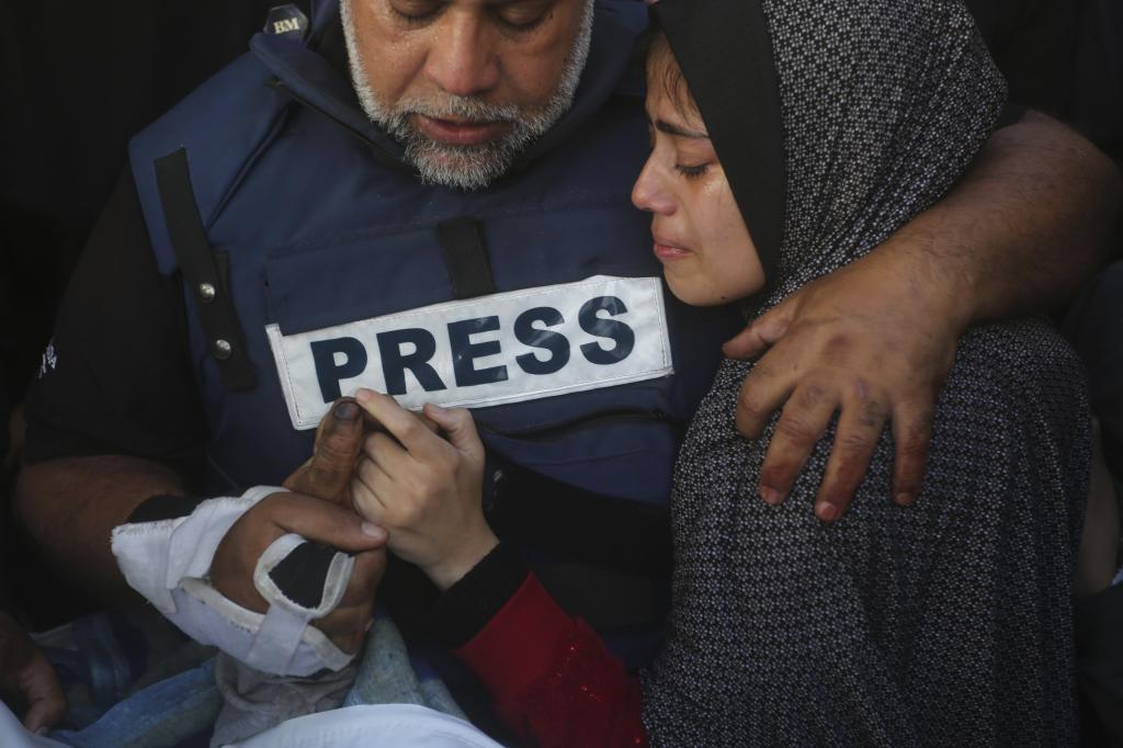 Al Jazeera journalist Wael Dahdouh holds the hand of his son, Hamza, who also worked for Al Jazeera and was killed in an Israeli airstrike