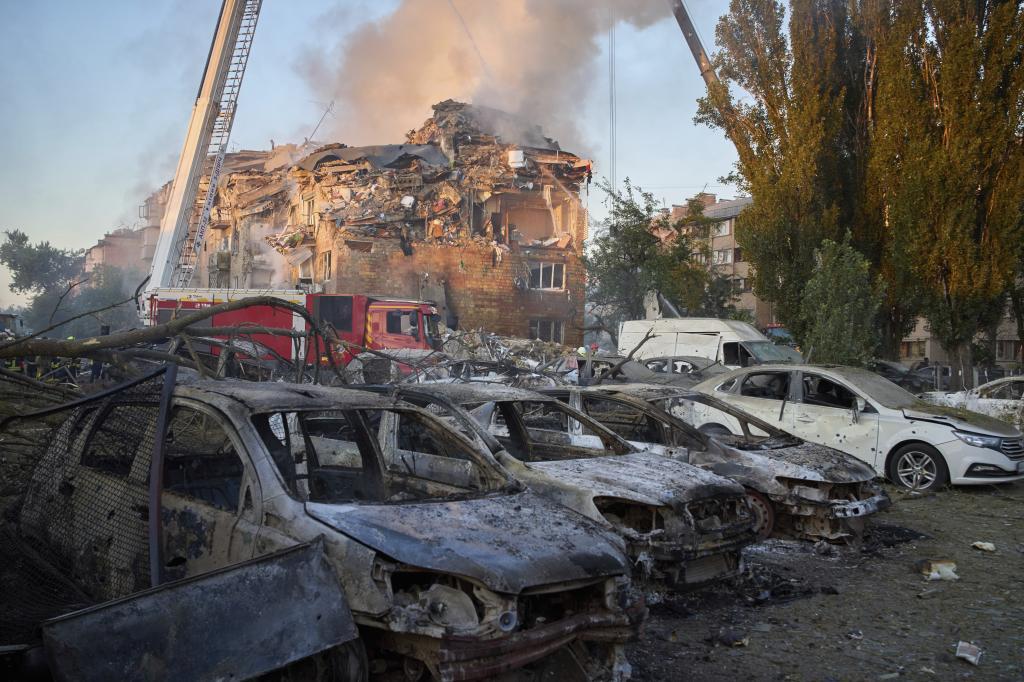 Cars are seen damaged in front of a destroyed residential building after a Russian missile attack in Kyiv