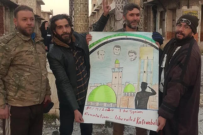 Cartoonist Yalal holding a banner in memory of three of his colleagues killed.