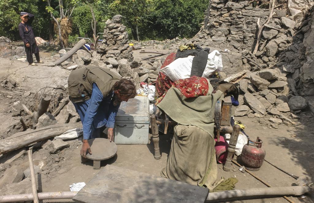 A man collects belongings from the rubble of a collapsed house after a powerful earthquake struck eastern Afghanistan