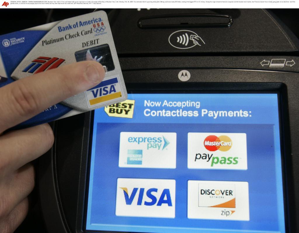 A Visa card holder holds up his card next to a credit card reader