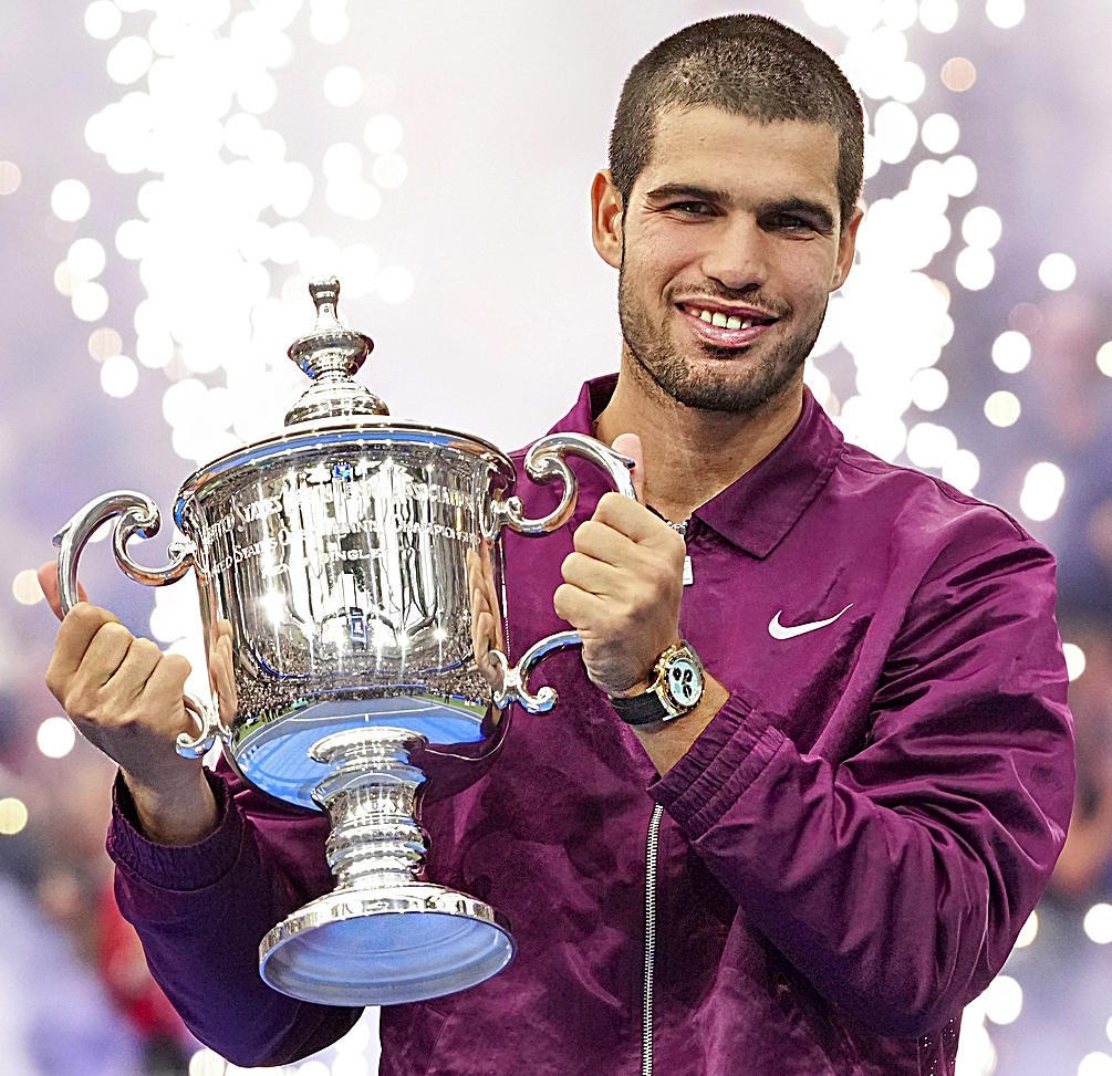 Carlos Alcaraz, of Spain, holds up the championship trophy.