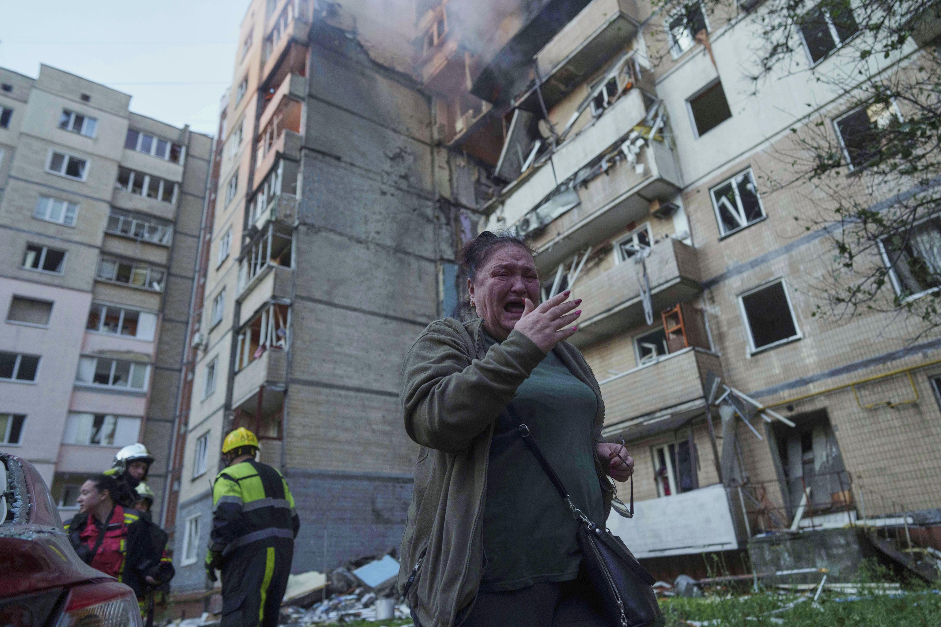A woman reacts in front of a building hit by a Russian attack in Kyiv.