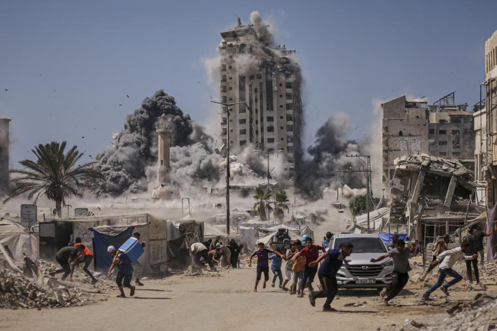 Palestinians run for cover during an Israeli airstrike on a high-rise building in Gaza City