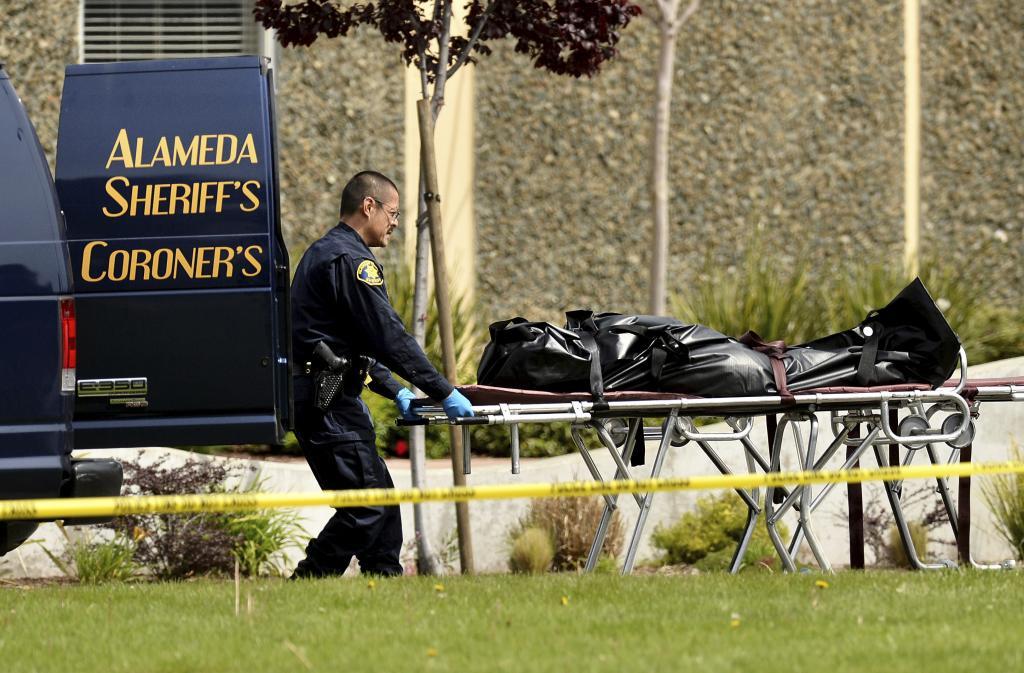 A sheriff's deputy removes a body from outside Oikos University in Oakland