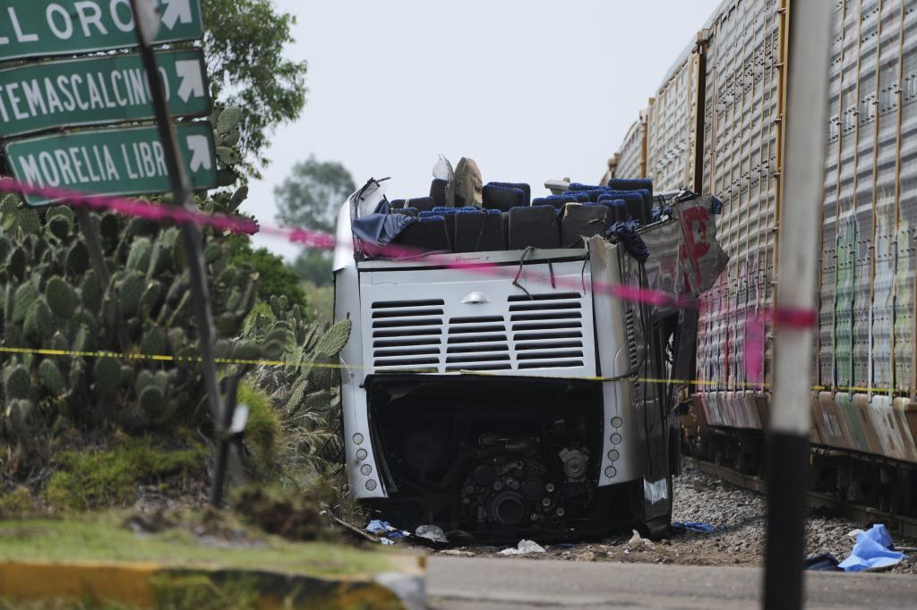Remains of a double-decker bus can be seen next to a freight train that hit it in Atlacomulco.