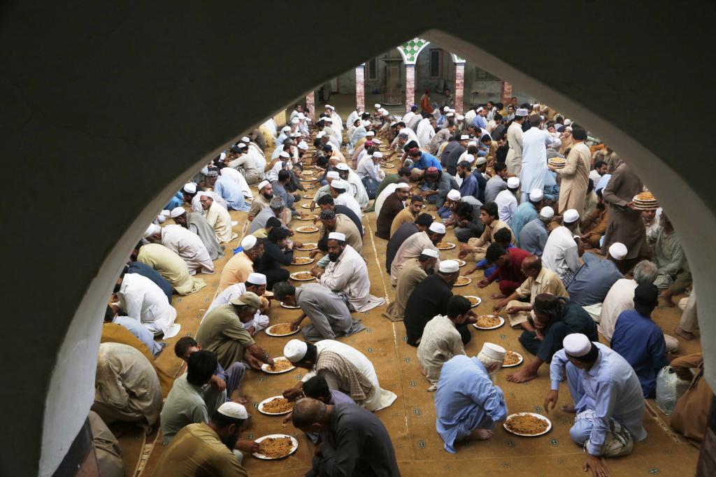 People eat meals distributed by volunteers, following a procession as they mark Prophet Muhammad's birthday,