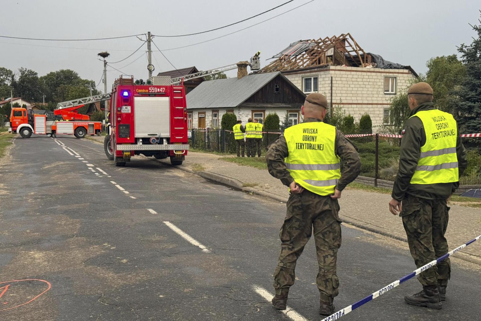 Firefighters stand close to the destroyed roof of a house, after Russian drones violated Polish airspace.
