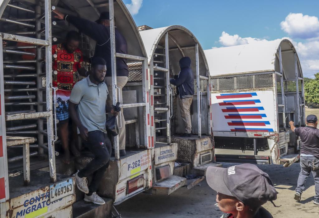Haitians deported from the Dominican Republic get out of trucks in Carrizal, Dominican Republic