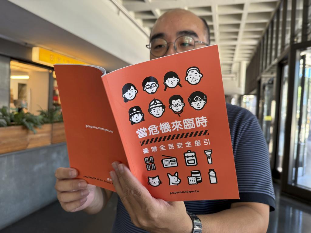 A man holds up a new civil defense handbook.