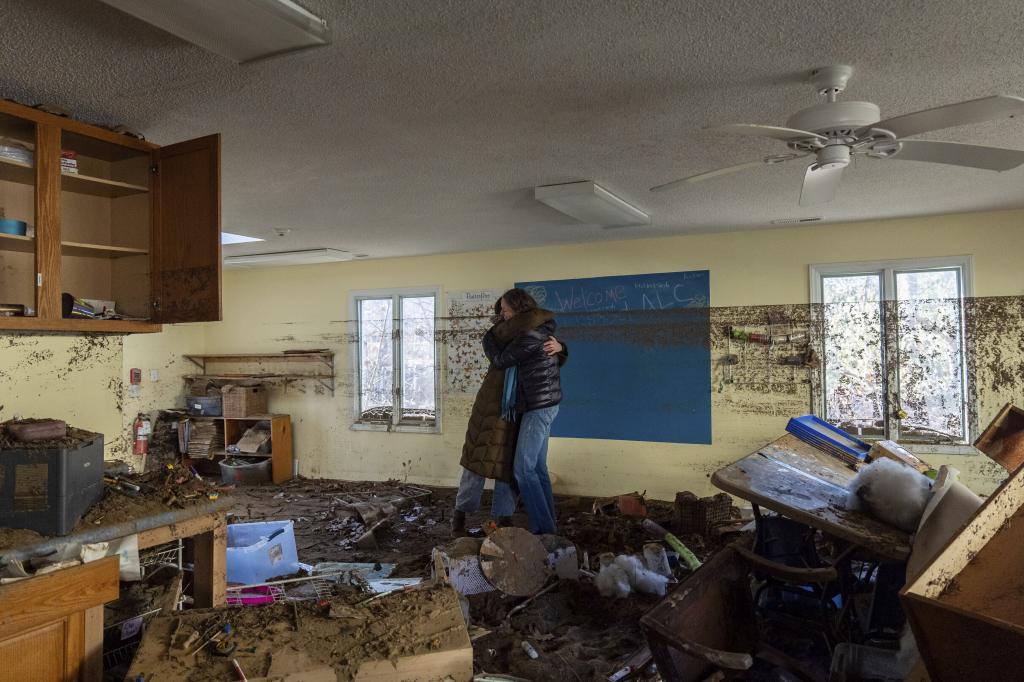 Nicole Schoychid, left, and Rebekah Canu, co-founders of the Wildwood Agile Learning Center, embrace at the school, which was damaged by flooding from Hurricane Helene.