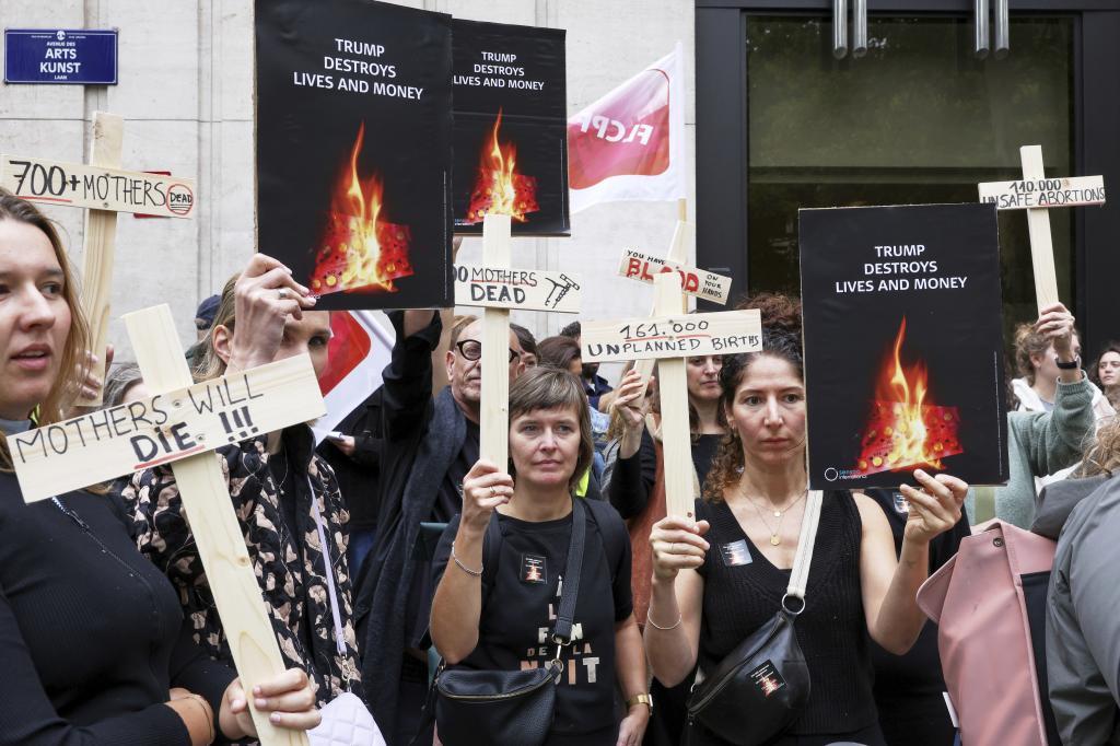 Participants from various women's rights organizations hold signs as they demonstrate regarding the destruction of family planning supplies stockpiled in Belgium
