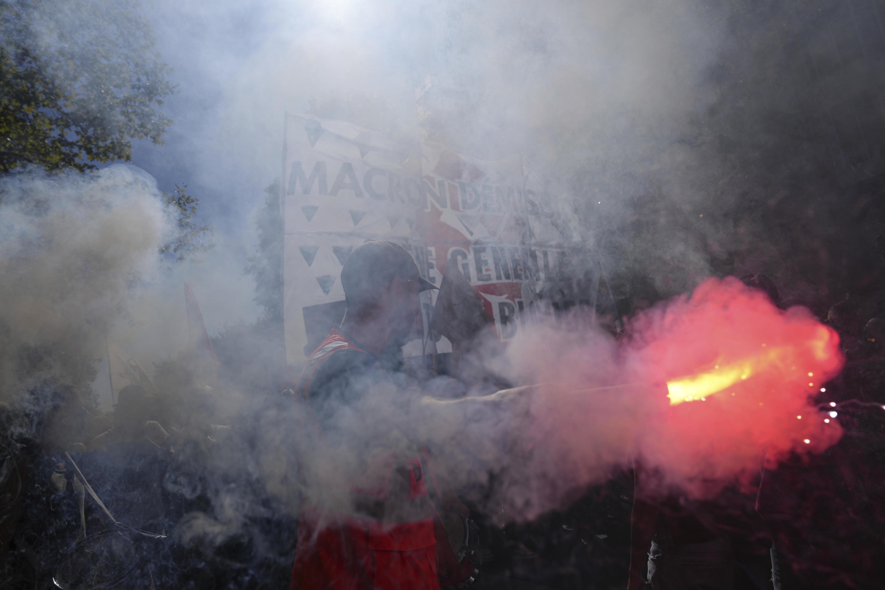 Protesters holding a banner reading in French ' Macron resignation '.