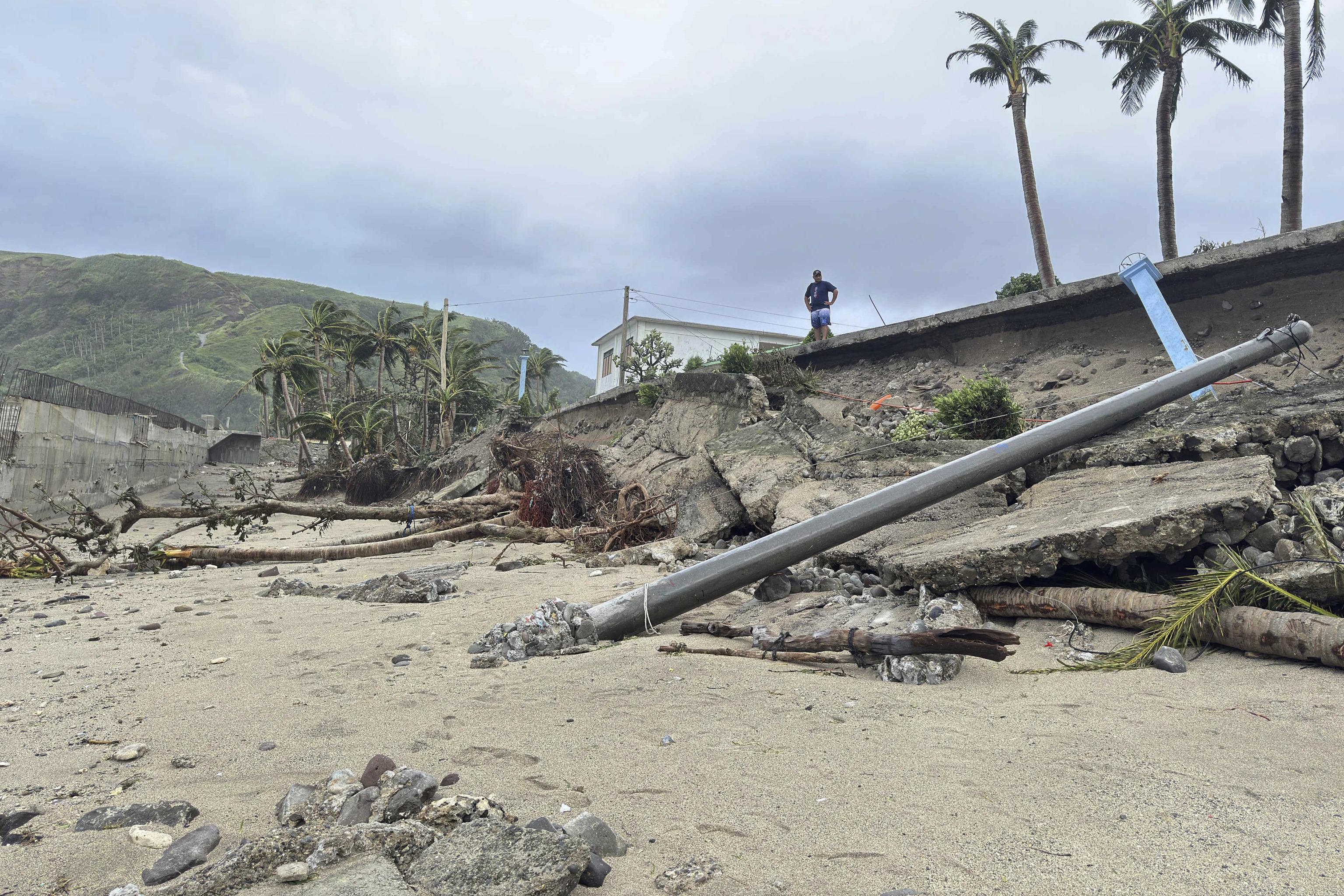 A man stands beside a damaged road due to Typhoon Ragasa in Uyugan.